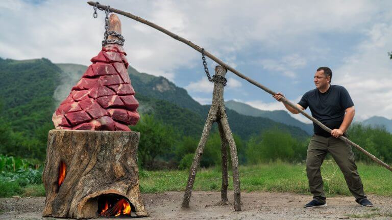 Slow-Cooked Beef Leg Inside a Smoldering Log Over Fire